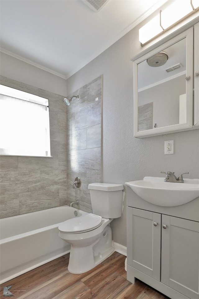 full bathroom featuring toilet, tiled shower / bath, vanity, ornamental molding, and hardwood / wood-style flooring