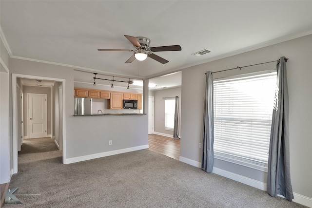 unfurnished living room with carpet flooring, ceiling fan, and crown molding