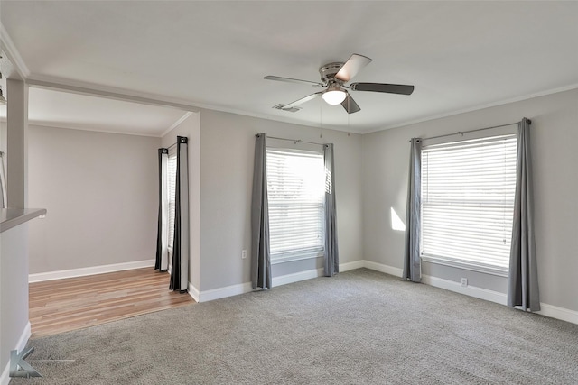 spare room featuring light carpet, crown molding, ceiling fan, and a healthy amount of sunlight