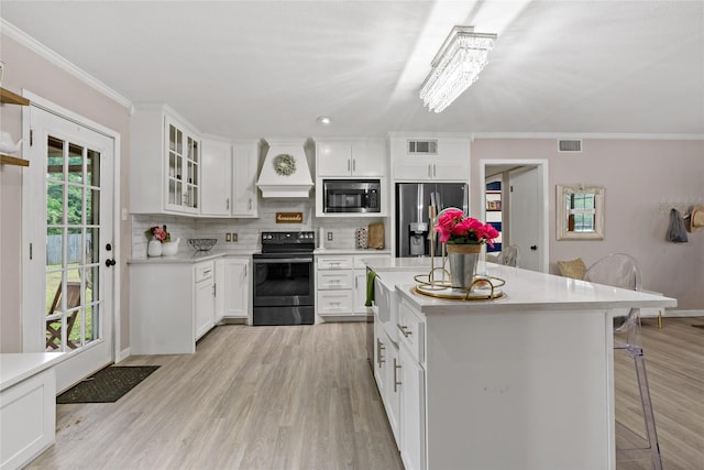 kitchen featuring white cabinetry, built in microwave, premium range hood, stainless steel fridge, and electric stove