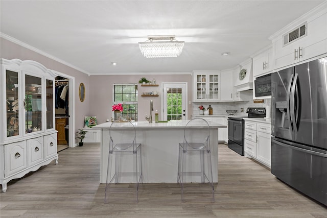 kitchen with black appliances, a center island, a kitchen bar, and white cabinetry