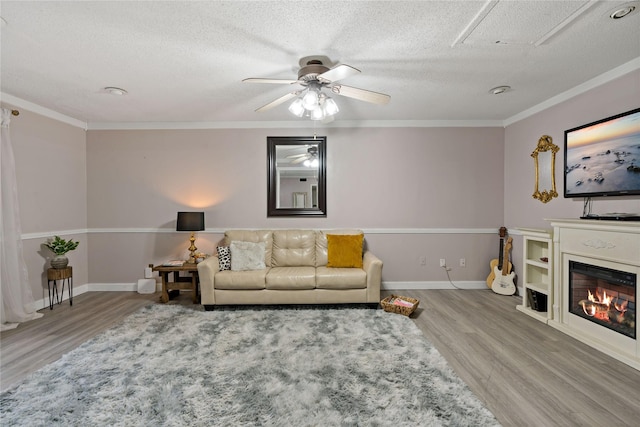 living room featuring a textured ceiling, ceiling fan, wood-type flooring, and crown molding