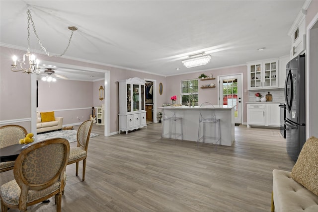 kitchen with stainless steel refrigerator, white cabinetry, pendant lighting, a kitchen bar, and ornamental molding