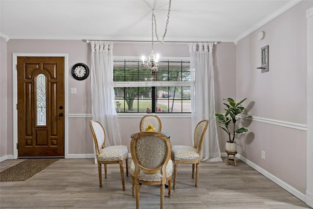 dining room with light wood-type flooring, crown molding, and an inviting chandelier