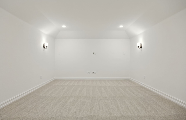 carpeted spare room with vaulted ceiling