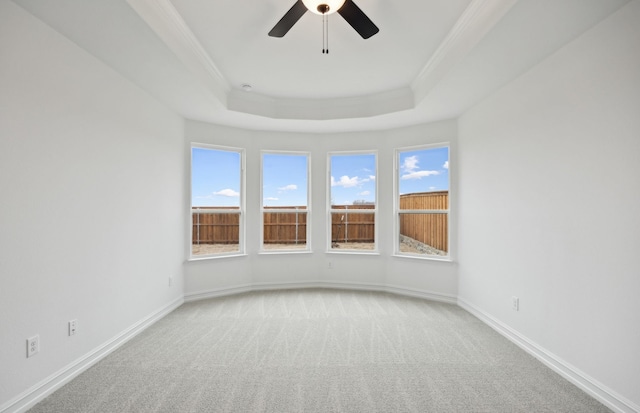 spare room with a tray ceiling, ornamental molding, light carpet, and a wealth of natural light