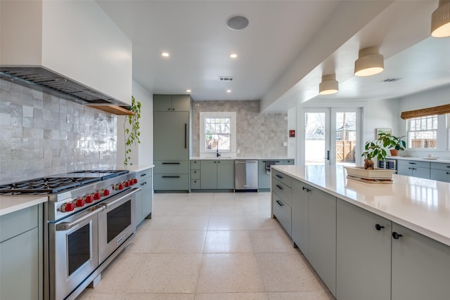 kitchen with appliances with stainless steel finishes, tasteful backsplash, wall chimney exhaust hood, and gray cabinetry