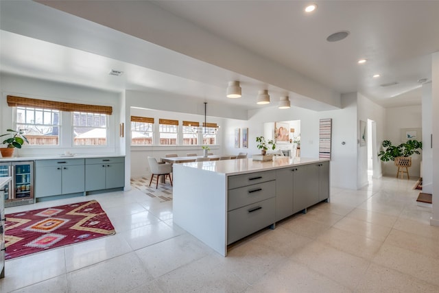 kitchen featuring a center island, decorative light fixtures, wine cooler, and gray cabinets