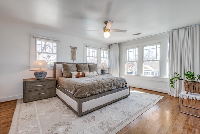 bedroom with multiple windows, light hardwood / wood-style floors, and ceiling fan