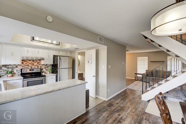 kitchen with white cabinetry, dark wood-type flooring, backsplash, exhaust hood, and appliances with stainless steel finishes