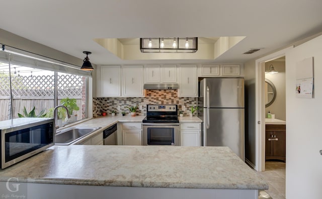 kitchen with appliances with stainless steel finishes, white cabinetry, a raised ceiling, and sink