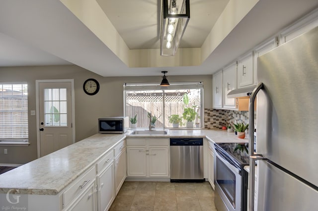 kitchen featuring a tray ceiling, sink, white cabinets, and appliances with stainless steel finishes