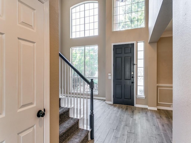 entryway featuring light wood-type flooring, ornamental molding, and a high ceiling