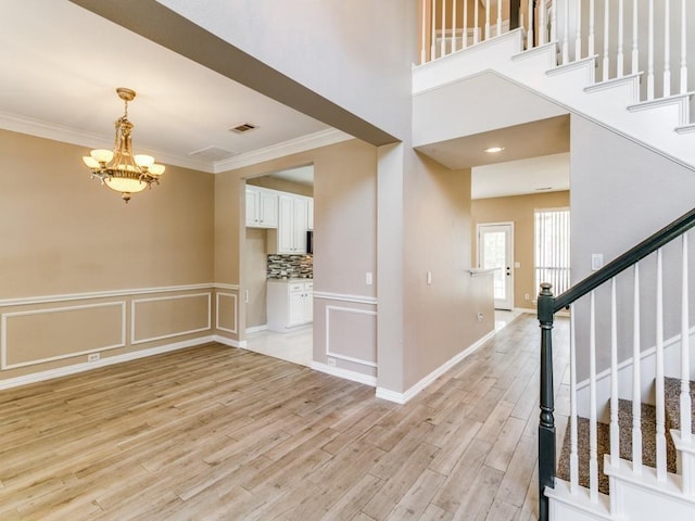 entryway with ornamental molding, light hardwood / wood-style floors, and an inviting chandelier