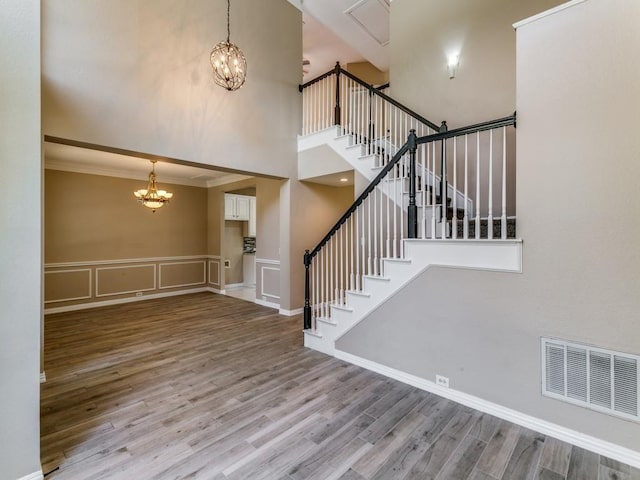 foyer entrance with a chandelier, a high ceiling, light hardwood / wood-style floors, and crown molding