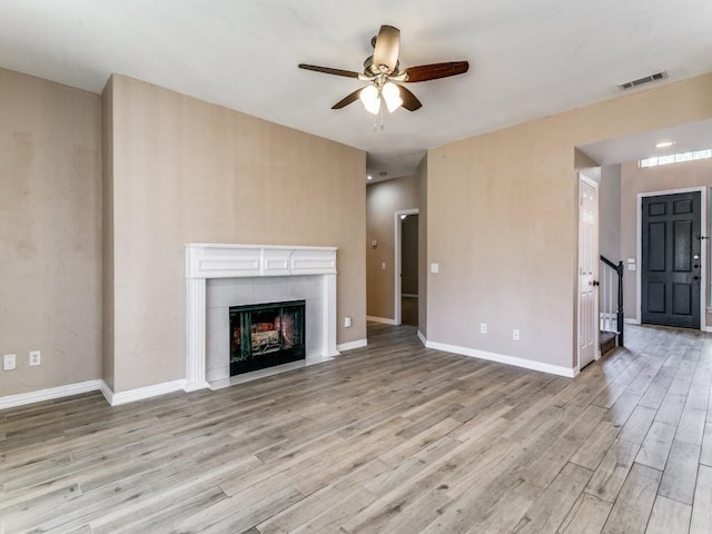 unfurnished living room featuring a fireplace, light wood-type flooring, and ceiling fan