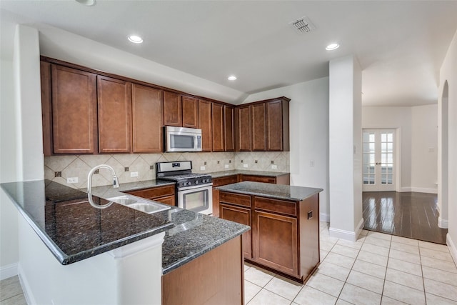 kitchen with french doors, sink, light tile patterned floors, appliances with stainless steel finishes, and kitchen peninsula