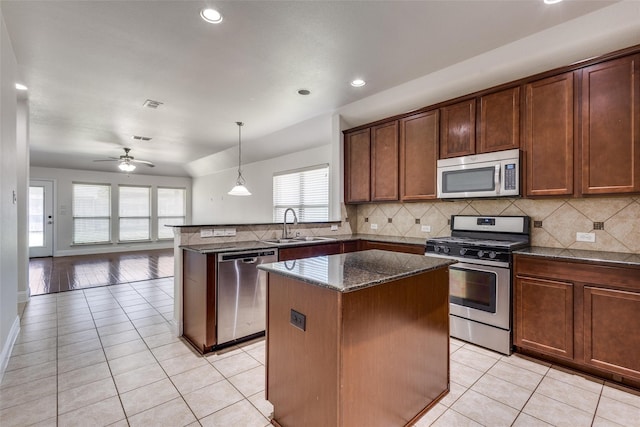 kitchen with ceiling fan, sink, hanging light fixtures, a kitchen island, and appliances with stainless steel finishes