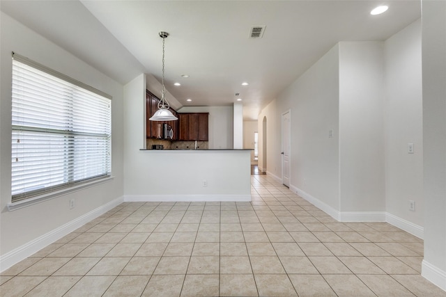 kitchen with kitchen peninsula, pendant lighting, backsplash, and light tile patterned floors