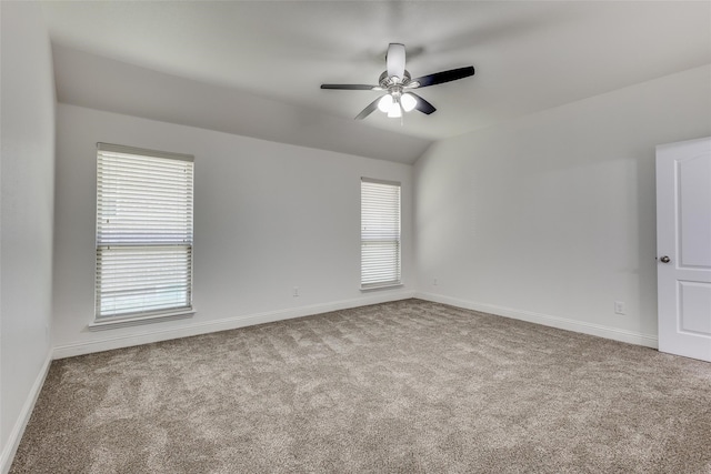 carpeted empty room with a wealth of natural light, ceiling fan, and lofted ceiling