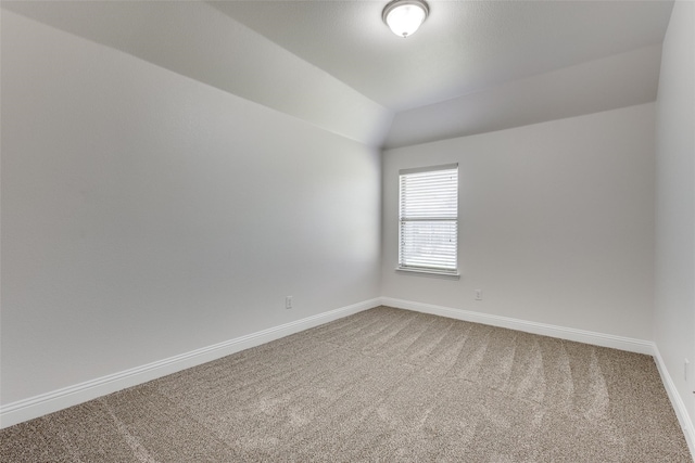 empty room featuring carpet and vaulted ceiling