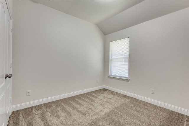 carpeted empty room featuring lofted ceiling