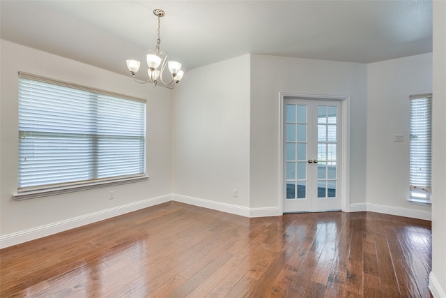 spare room featuring french doors, hardwood / wood-style flooring, and a notable chandelier