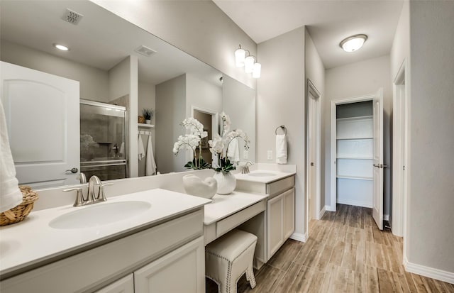 bathroom featuring vanity, wood-type flooring, and a shower with door