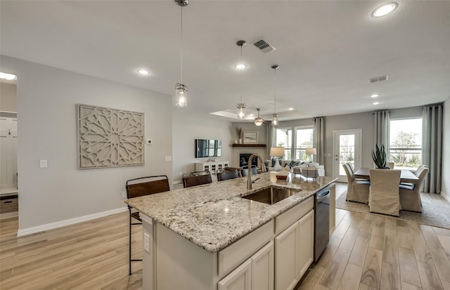 kitchen featuring pendant lighting, sink, stainless steel dishwasher, and a center island with sink