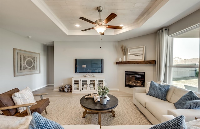 living room featuring crown molding, ceiling fan, a raised ceiling, and light hardwood / wood-style floors