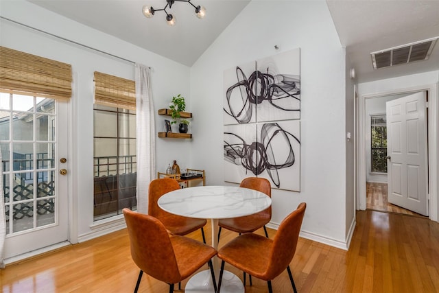 dining room with plenty of natural light, vaulted ceiling, and light wood-type flooring