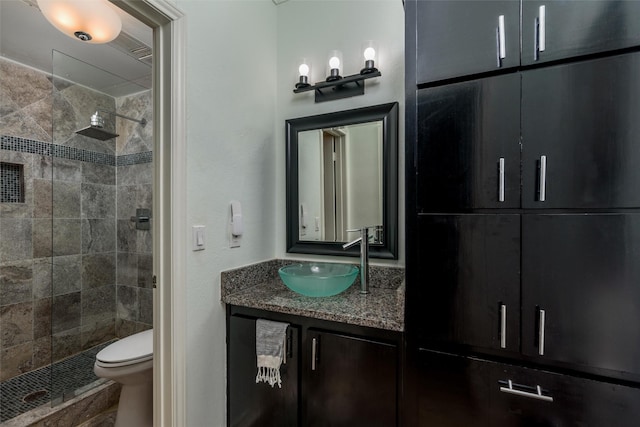 bathroom featuring vanity, toilet, and a tile shower