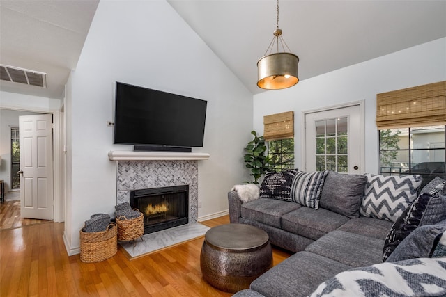 living room featuring a tiled fireplace, hardwood / wood-style floors, and high vaulted ceiling