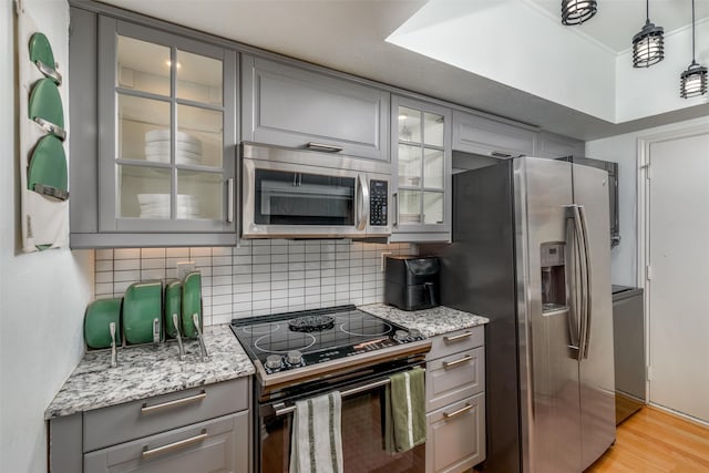 kitchen with appliances with stainless steel finishes, light stone countertops, hanging light fixtures, and gray cabinetry