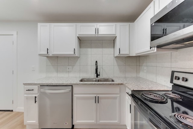 kitchen with appliances with stainless steel finishes, sink, white cabinets, and light stone counters