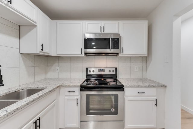 kitchen featuring tasteful backsplash, white cabinets, and appliances with stainless steel finishes