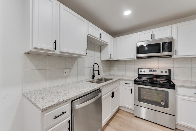 kitchen featuring backsplash, stainless steel appliances, sink, and white cabinets