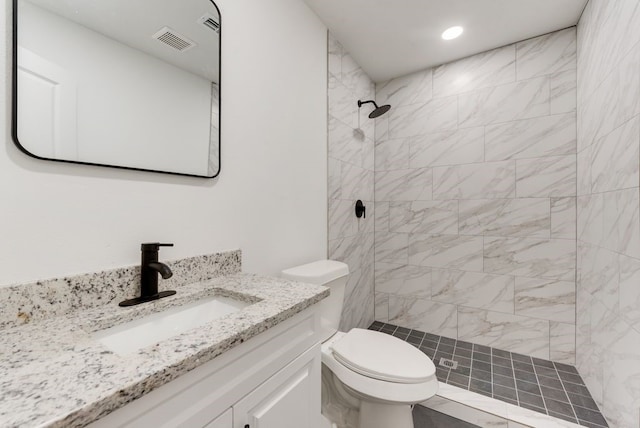 bathroom with vanity, tiled shower, and toilet