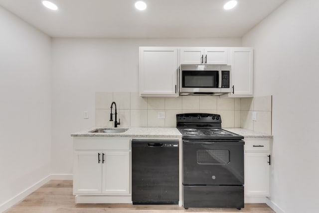 kitchen featuring sink, white cabinets, light stone counters, and black appliances