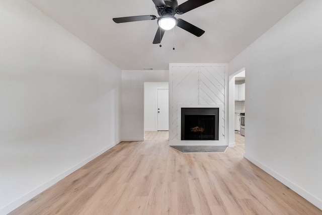 unfurnished living room featuring a premium fireplace, ceiling fan, and light hardwood / wood-style floors