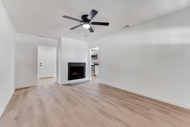 unfurnished living room with ceiling fan, a high end fireplace, and light hardwood / wood-style flooring