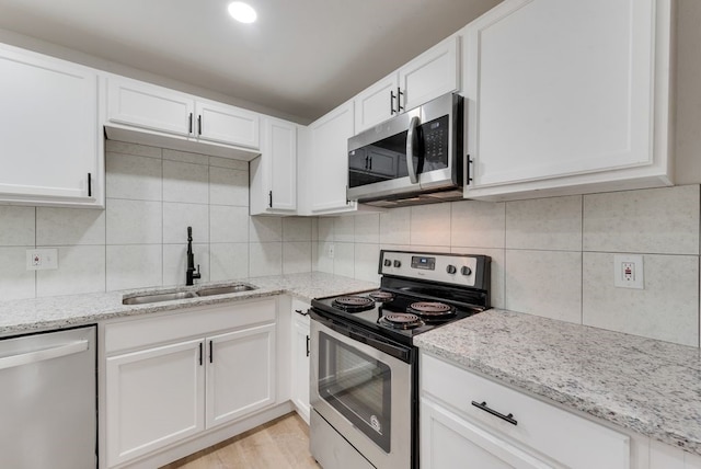 kitchen with sink, backsplash, white cabinets, and appliances with stainless steel finishes