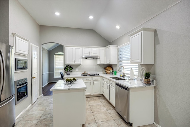 kitchen featuring appliances with stainless steel finishes, vaulted ceiling, sink, a center island, and white cabinetry