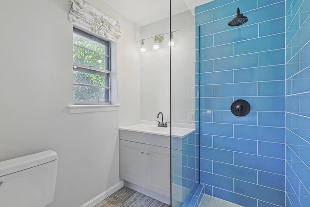 bathroom featuring vanity, tiled shower, and toilet