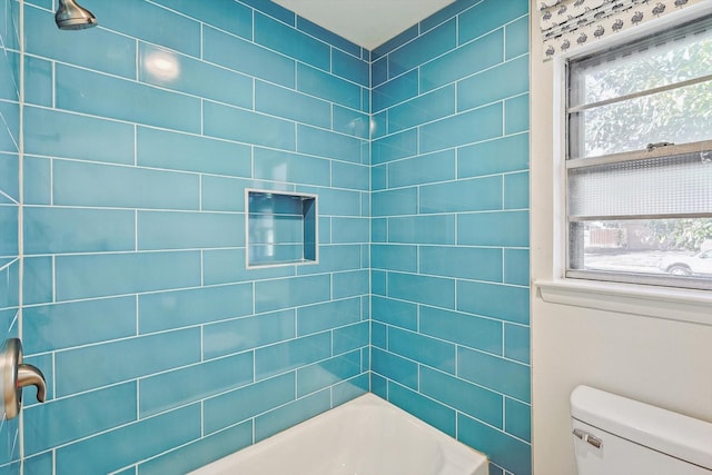 bathroom with tiled shower / bath combo, plenty of natural light, and toilet