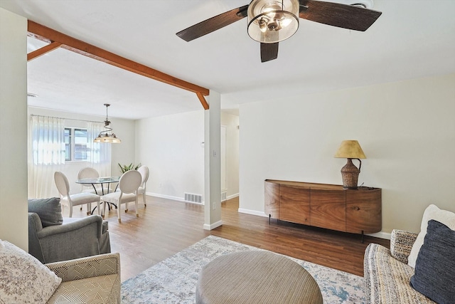 living room featuring hardwood / wood-style floors, beamed ceiling, and ceiling fan