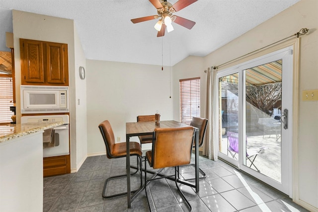 tiled dining space featuring a textured ceiling, ceiling fan, and lofted ceiling