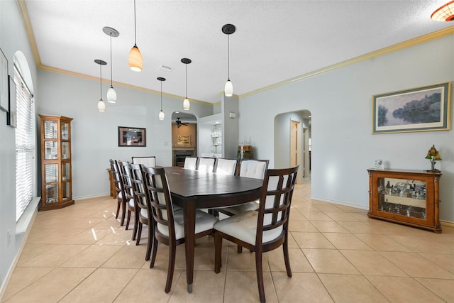 dining space with ceiling fan, light tile patterned flooring, ornamental molding, and a textured ceiling