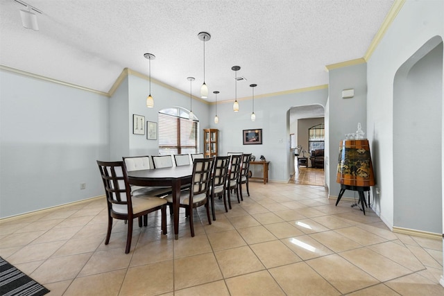 tiled dining room featuring a textured ceiling, lofted ceiling, and crown molding