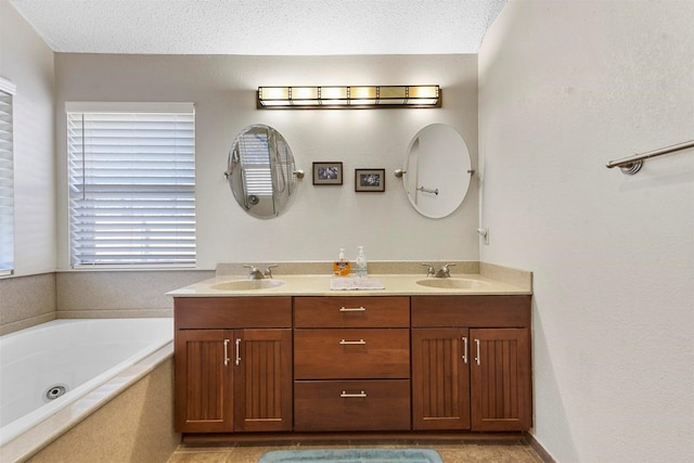 bathroom with vanity, a textured ceiling, and tiled bath